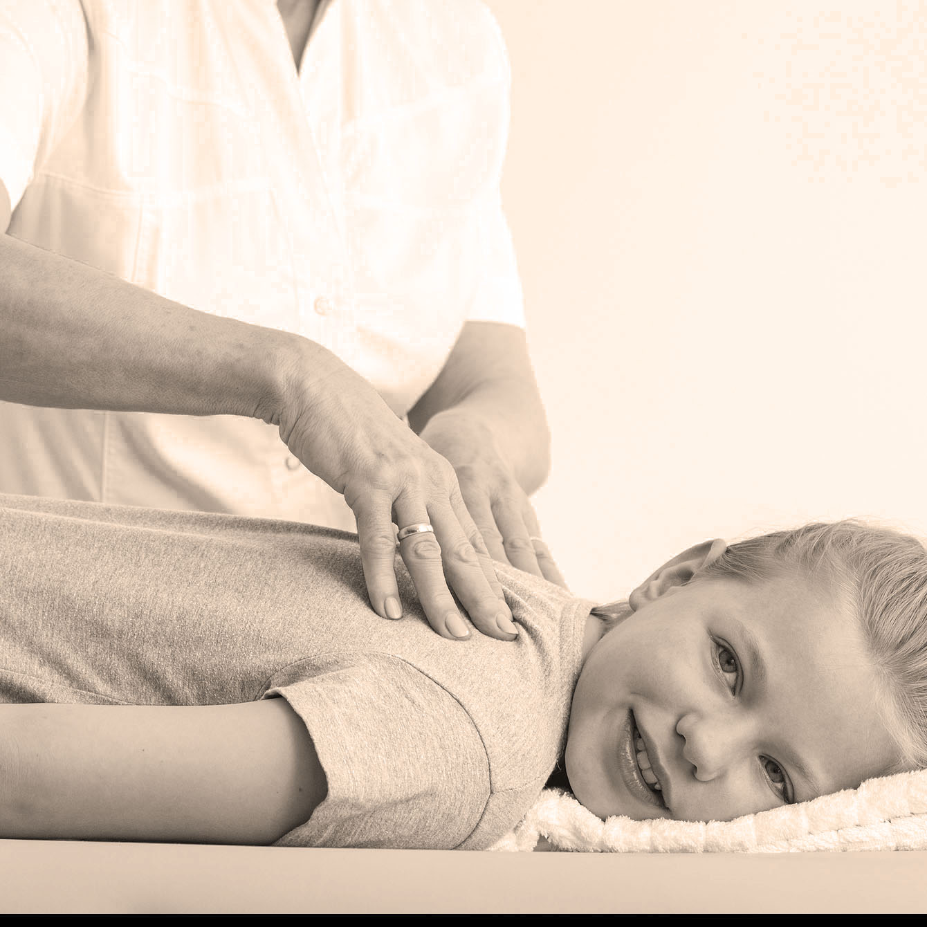 Girl lying on physiotherapy table and having back massage by chiropractor